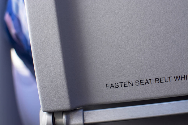 座席背面のテキスト「を留めるシートベルト...」クローズ アップと飛行機インテリア. - 写真・画像