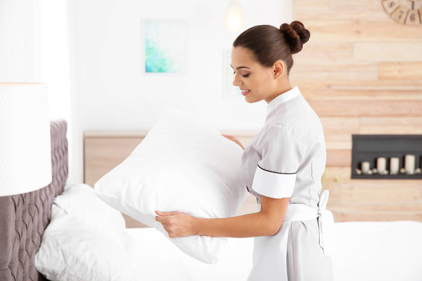 Young chambermaid making bed in hotel room - Фото, зображення