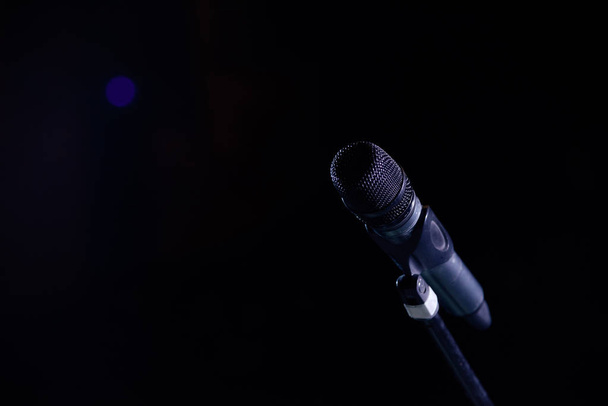 Closeup of microphone in concert hall or conference room on dark hall background - Fotó, kép