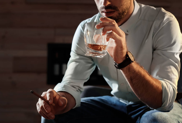 Man with glass of whiskey and cigar at home, closeup. Space for text - Photo, image