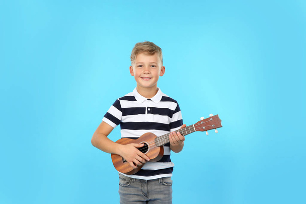 Portrait of little boy playing guitar on color background - Фото, зображення
