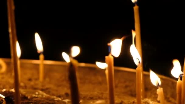 Воскові свічки горять у темряві в церкві на тлі темного фону крупним планом руху камери, повільний рух
 - Кадри, відео