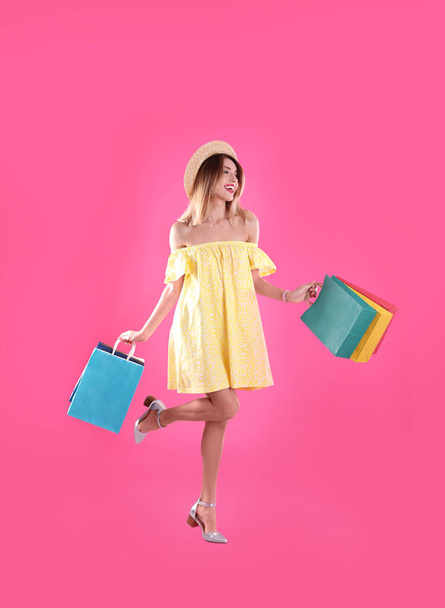 Beautiful young woman with shopping bags on color background - Valokuva, kuva