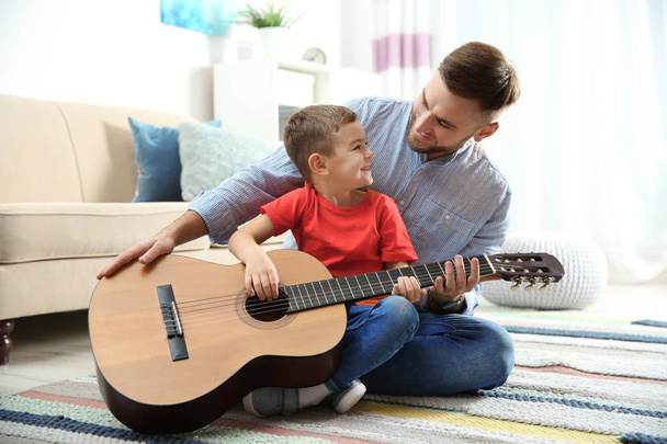 Father teaching his little son to play guitar at home - Zdjęcie, obraz
