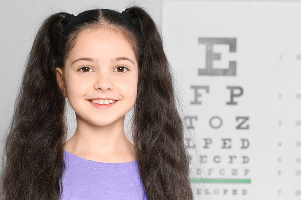 Portrait of cute little girl visiting children's doctor, space for text. Eye examination - Foto, imagen