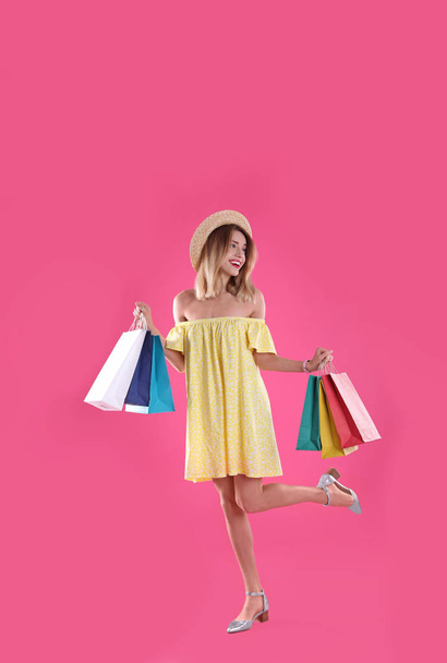 Beautiful young woman with shopping bags on color background - Photo, Image