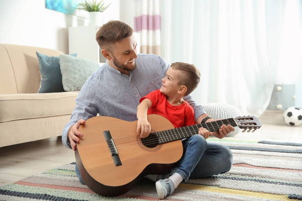 Father teaching his little son to play guitar at home - Fotoğraf, Görsel