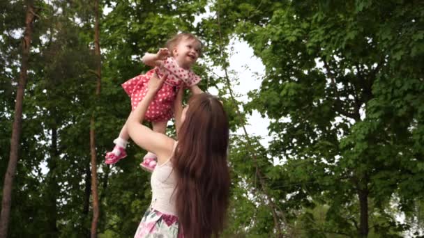 Mamá lanza al bebé alto en el aire, riéndose y jugando con ella en el parque. Mamá e hija ríen y descansan en la ciudad
. - Metraje, vídeo