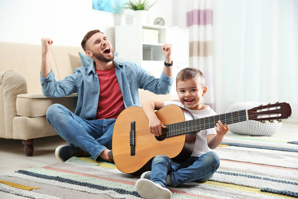 Отец и сын играют на гитаре и поют дома
 - Фото, изображение