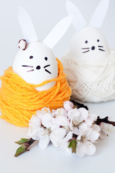 Conejo de Pascua decorativo y flores de cerezo sobre un fondo blanco
 - Foto, Imagen