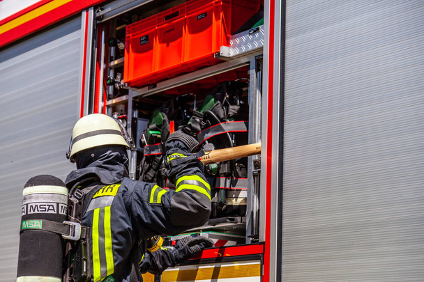 Hannover / Duitsland - 6 juli 2017: Duitse brandweerman neemt een object uit een brandweerwagen - Foto, afbeelding