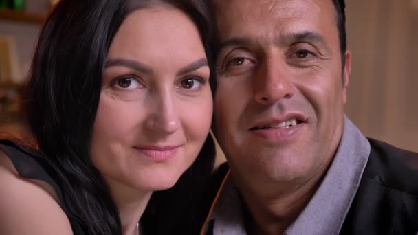 Nahaufnahme Porträt eines sich umarmenden arabischen Paares, das lächelnd in die Kamera schaut, mit seinen Kindern im Hintergrund. - Filmmaterial, Video