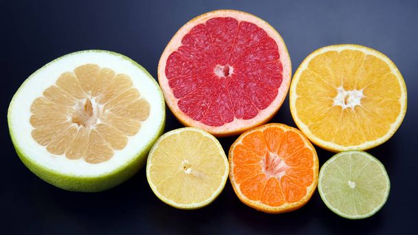 срезать куски различных цитрусовых фруктов на темную спинку
 - Фото, изображение