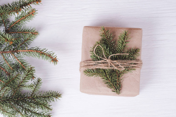 Caja de regalo de Navidad sobre fondo de madera blanca. Marco de ramas de abeto
, - Foto, imagen