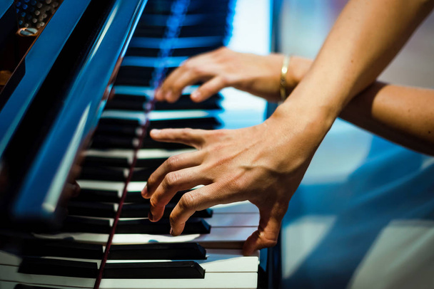Пианист играет на черном пианино. руки пианиста на фоне черно-белых клавиш. концерт
 - Фото, изображение