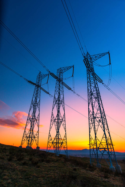 arancio tramonto cielo e trasmissione pali elettrici in campo rurale
  - Foto, immagini