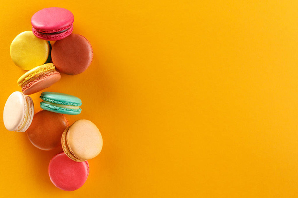 Sweet and colorful french macaroons on a yellow background. Dessert is with tea or coffee. Space under the text. - Фото, изображение