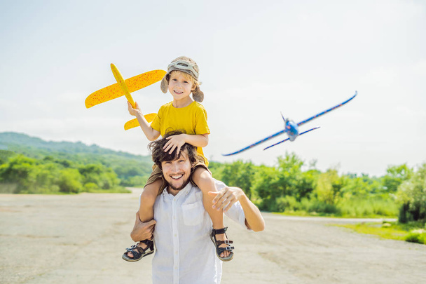 Happy father and son playing with toy airplanes in countryside - Foto, Imagen
