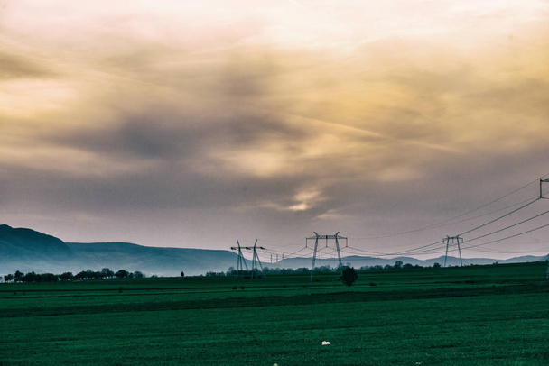 Field with electricity poles and sunset sky background - Fotó, kép
