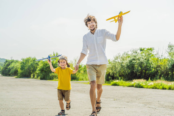 Happy father and son running and playing with toy airplanes in countryside - Fotó, kép