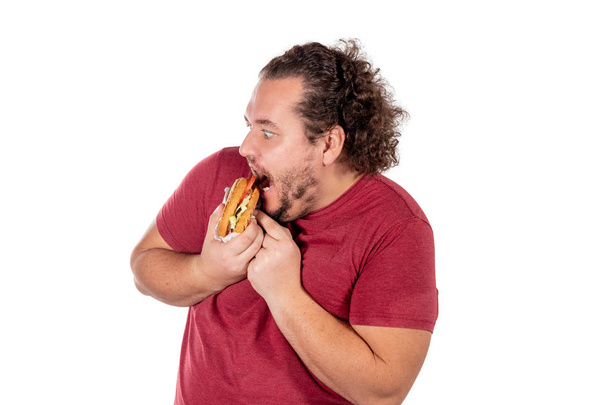 Funny fat man eating hamburger. Fast food, unhealty eat. Overweight and health problems - Foto, Imagen