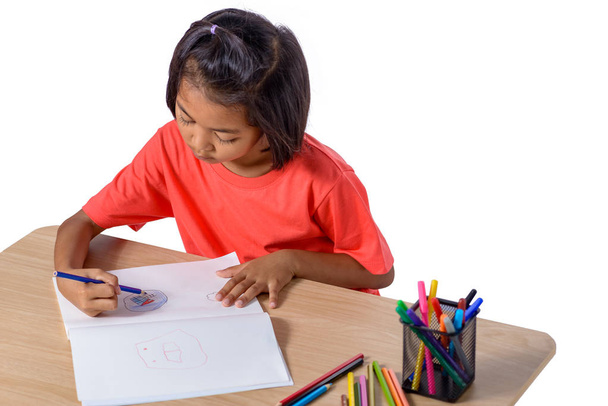 Cute cheerful child drawing using color pencil while sitting at table isolated on white background with clipping path. Education study home school - Photo, image