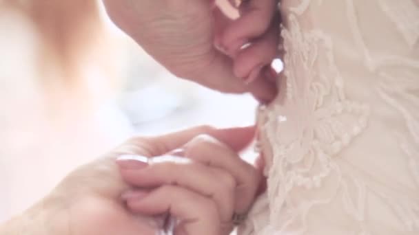 白いドレスのボタンは結婚式で花嫁に留まります。コルセットのボタン - 映像、動画