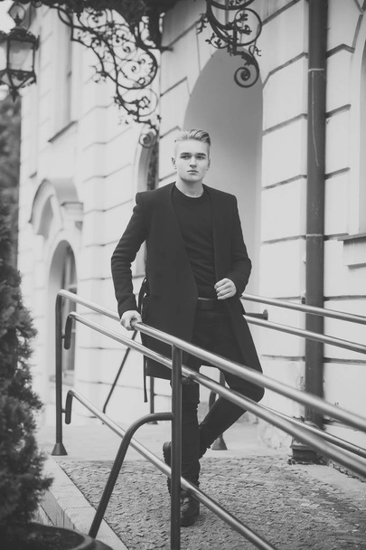 Young man in black outfit walks in old city. - Foto, afbeelding