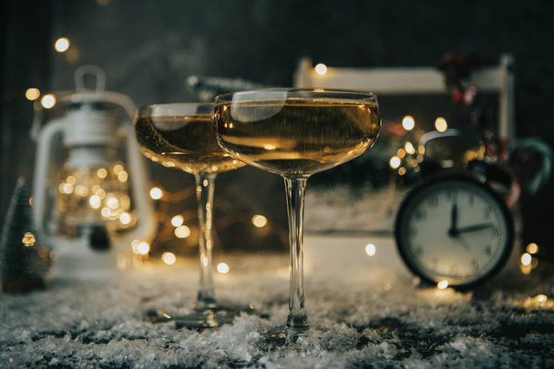 クリスマス ツリー、ランタン、時計と背景をぼかした写真の二つのワイングラスの絵 - 写真・画像