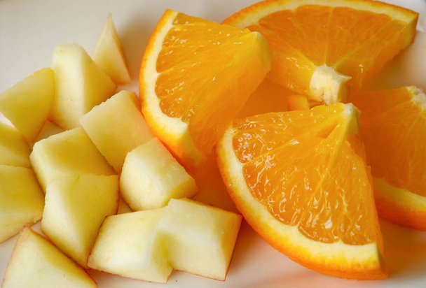 φέτα φρούτα στο άσπρο πιάτο / κοντινό φρέσκια φέτα πορτοκάλι και μήλο φρούτα   - Φωτογραφία, εικόνα