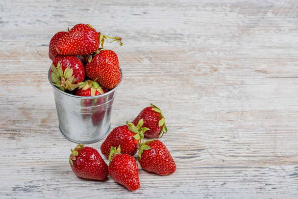 A bucket of fresh ripe strawberries, close-up on a light wooden background, copy space. - Foto, immagini