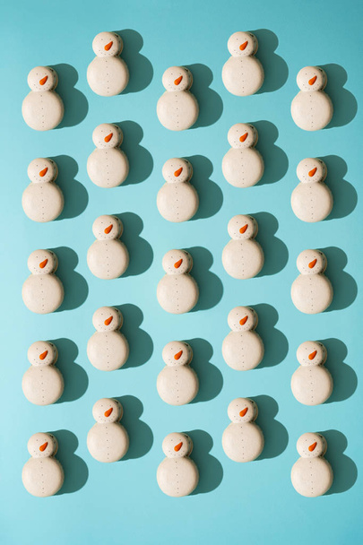 Variety of sweet macaroons in form of snowmen on pastel blue background - Foto, Imagem