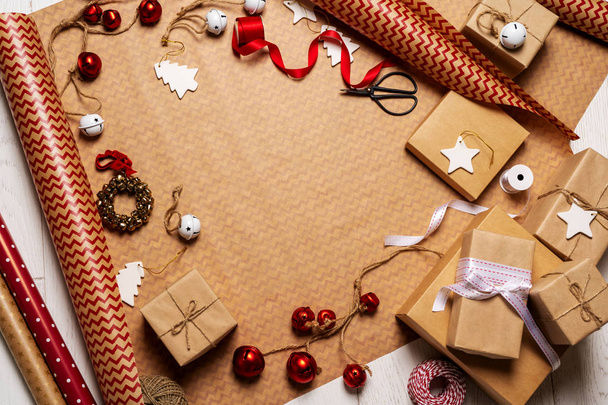 Bovenaanzicht van geschenkdozen, packing tapes, touw, papier rollen en decoraties rekwisieten op inpakpapier - Foto, afbeelding