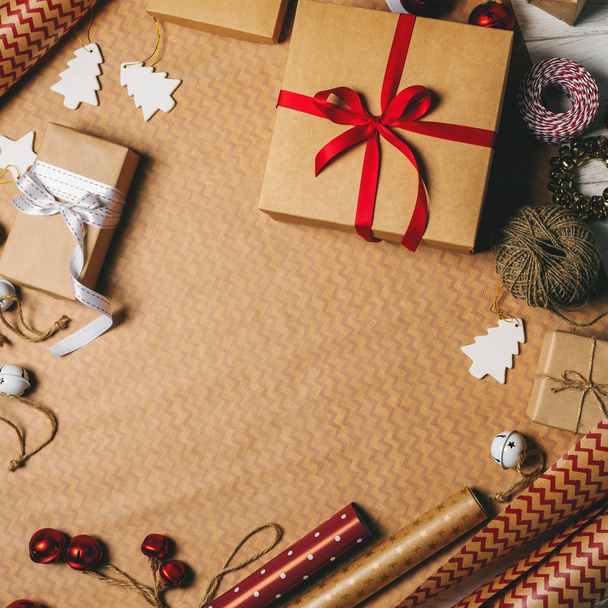 Top view of gift boxes, packing tapes, rope, paper rolls and decorations props on wrapping paper - 写真・画像