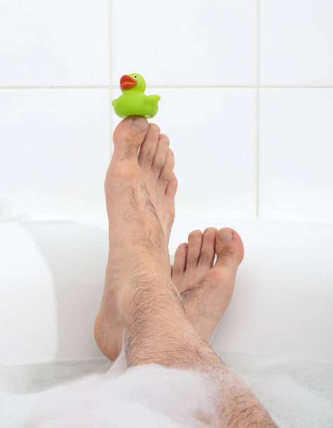 Los pies de los hombres en una bañera blanca brillante, enfoque selectivo en los dedos de los pies - Foto, Imagen