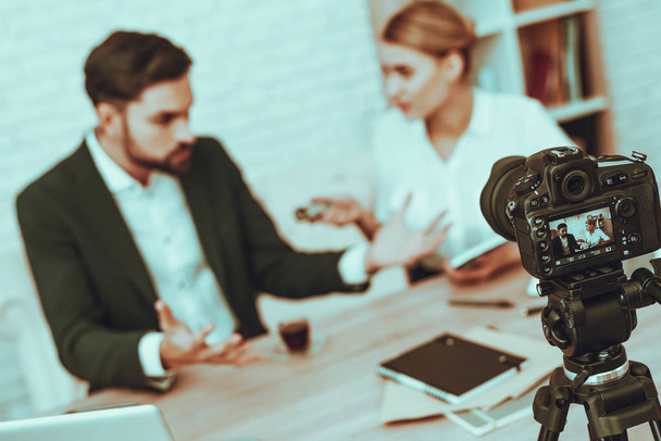 Blur Image of Journalist is Interviewing a Businessman. Journalist Using a Dictaphone. Camera Shoots a Video. Journalist is Beautiful Woman. Gadgets and Supplies on Table. People in Studio Interior. - 写真・画像