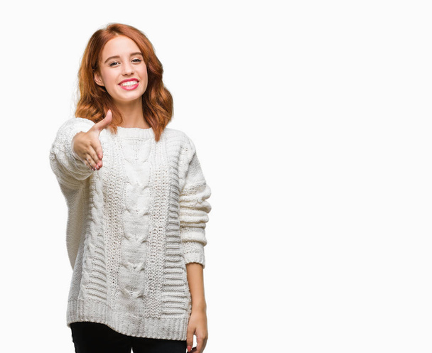 Młoda piękna kobieta na białym tle swetrze zima uśmiechający się oferujący przyjazny uścisk dłoni jako pozdrowienie i przyjazna. Udanego biznesu. - Zdjęcie, obraz
