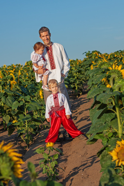 A father and two children in Ukrainian costume at sunset in a fi - 写真・画像