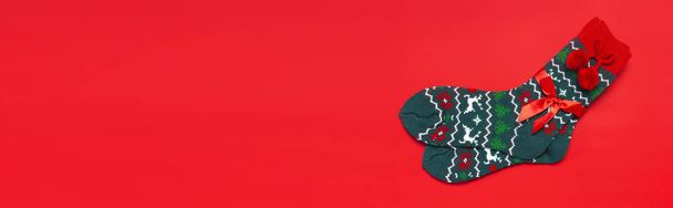 Vlněné ponožky s novoroční vánoční ornament na červené pozadí pohledu shora plochý lay. Dovolená concept, slavnostní ponožky, dárky Vánoce. Blahopřejeme pozadí s místem pro text oblečení na zimu - Fotografie, Obrázek