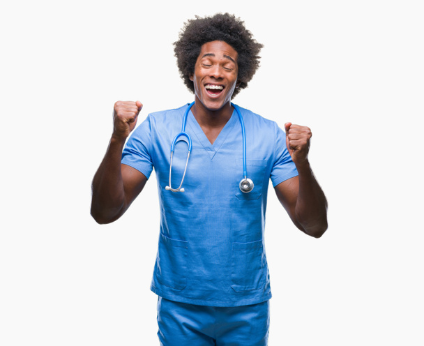 Afro-américain chirurgien médecin homme sur fond isolé excité pour le succès avec les bras levés célébrer la victoire en souriant. Concept gagnant
. - Photo, image