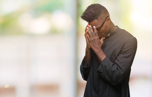 Jonge priester van de Afro-Amerikaanse man over geïsoleerde achtergrond met trieste uitdrukking waarin gezicht met handen terwijl het huilen. Depressie concept. - Foto, afbeelding