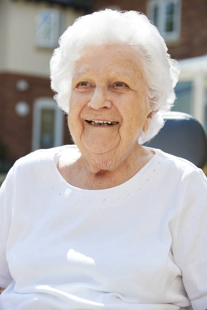 Portrait Of Senior Woman Sitting Outside Retirement Home - Фото, изображение