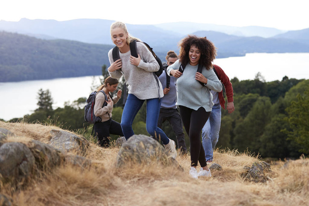 Group of five young adult friends smiling while hiking together to a mountain summit - Foto, Bild