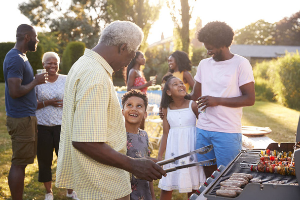 Nonno e nipote che parlano alla griglia a un barbecue di famiglia
 - Foto, immagini