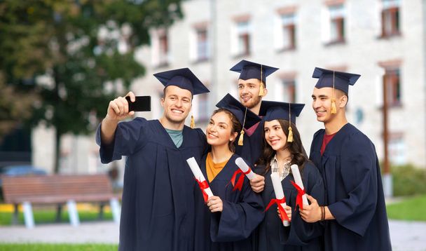 graduates with diplomas taking selfie by cellphone - Foto, Imagem