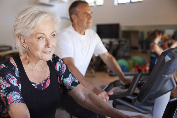 Active Senior Couple Exercising On Cycling Machines In Gym - Valokuva, kuva