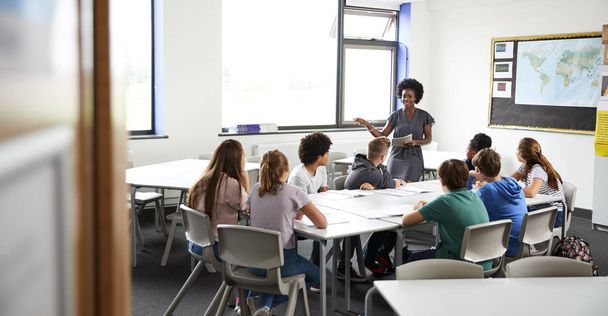 Жінка середньої школи Репетитор стоїть за столом зі студентами Урок викладання
 - Фото, зображення