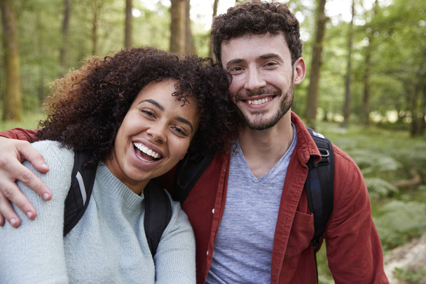 Young adult mixed race couple laughing to camera during a hike in a forest, portrait - Foto, Bild
