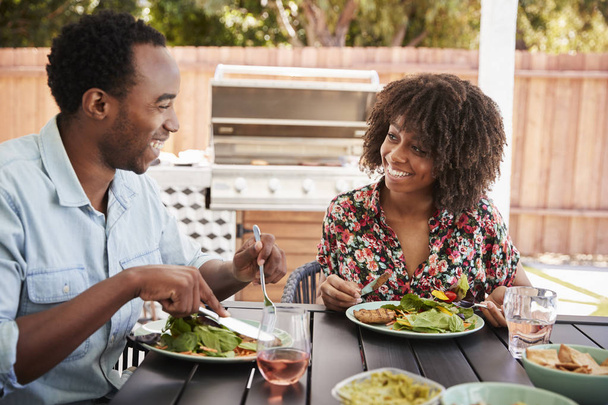 Young black couple eating lunch at a table in the garden - 写真・画像