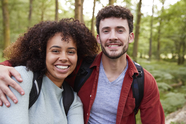 Young adult mixed race couple smiling to camera during a hike in a forest, portrait - Foto, afbeelding